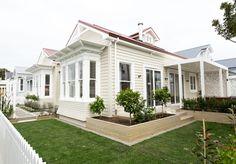 a small white house sitting on top of a lush green field next to a white picket fence