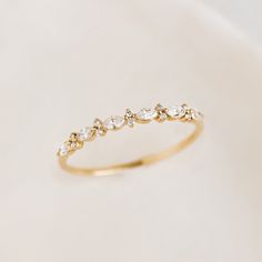 a gold ring with five small diamonds on the top and bottom, sitting on a white surface