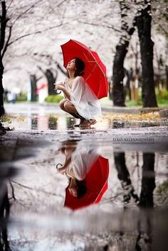 a woman kneeling on the ground holding an umbrella