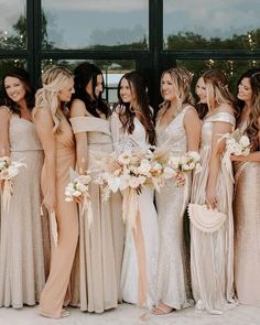 a group of women standing next to each other wearing dresses and holding bouquets in their hands