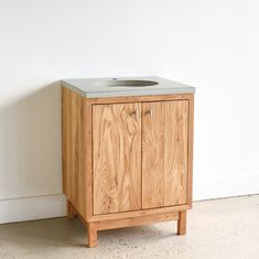 a wooden cabinet with a sink on top of it next to a white wall and floor