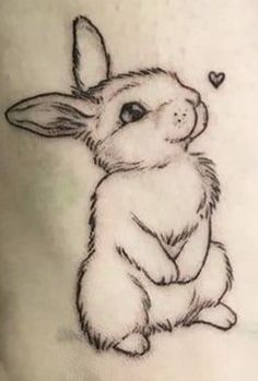 a small tattoo of a rabbit on the side of a woman's leg with a heart