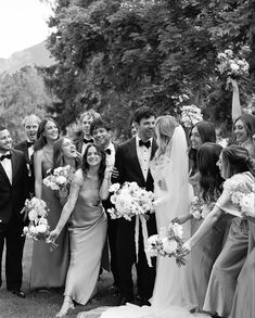 a group of people standing next to each other in front of trees and flowers on the grass