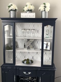 a black china cabinet with white flowers on top