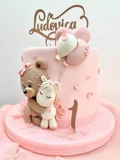 a pink cake with a teddy bear and number one on it's icing