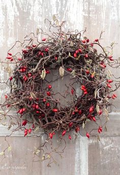 a wreath with red berries hanging on a door