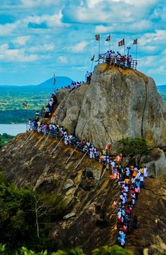 a group of people standing on top of a mountain next to a body of water