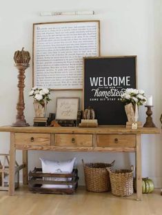 a wooden table topped with baskets filled with flowers and vases next to a welcome sign