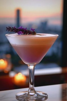 a drink in a martini glass with lavender sprigs on the rim