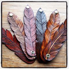 three different colored feathers sitting on top of a wooden table