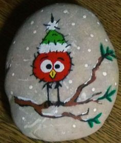 a painted rock with an owl wearing a santa hat on it's head sitting on a table