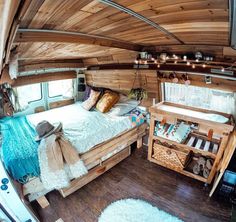 the interior of an rv with wood walls and flooring, including a bed in it