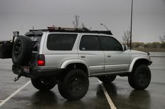 a white four door suv parked in a parking lot with its luggage on the back