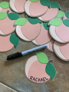 some pink and green apples cut out on the ground next to a marker with name rachel