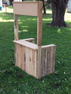 a bench made out of wooden pallets in the grass near a tree and fence