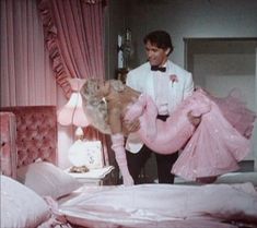 a man in a tuxedo is holding a woman's dress while standing on a bed