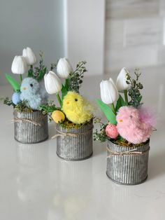 three tin can vases with flowers and stuffed animals in them sitting on a table