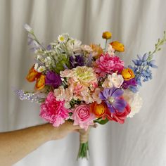 a bouquet of flowers is being held by a person's hand on a white background