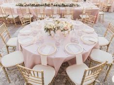 an outdoor wedding reception set up with pink linens and gold chairs