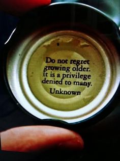 a person holding a can with a quote on it in front of the caption do not regt growing older, it is a pril