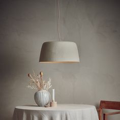 a table with a vase on it and a light hanging over it in the corner