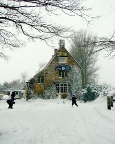 two people walking in the snow near a building