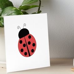 a red ladybug with black spots sitting on top of a table next to a potted plant