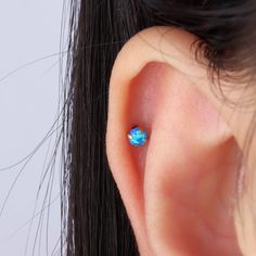 a woman's ear with an opal piercing in the middle of her ear