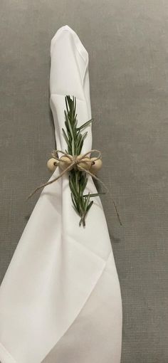 a white napkin tied with twine and green sprigs on top of it