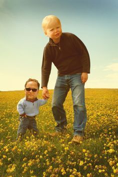 a man holding the hand of a little boy in a field full of yellow flowers