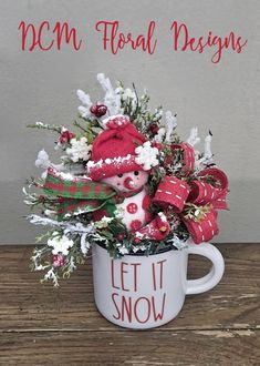 a mug filled with flowers and a teddy bear sitting in the cup that says mcm floral designs let it snow