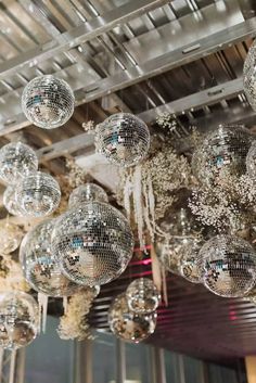 disco ball chandelier hanging from the ceiling in an indoor event venue with white flowers and greenery