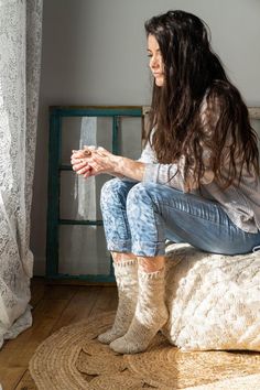 a woman sitting on top of a bed next to a window