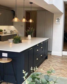 a kitchen with an island and two stools in front of the counter top, surrounded by potted plants