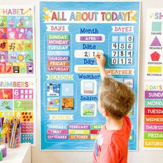 a young boy writing on a bulletin board with calendars and numbers attached to it