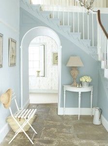 a white table sitting under a stair case next to a blue painted wall in a living room