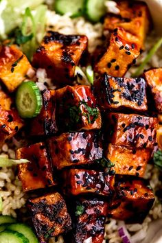 a bowl filled with tofu, rice and cucumbers