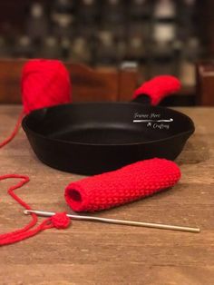 red crocheted yarn next to a skillet and knitting needles