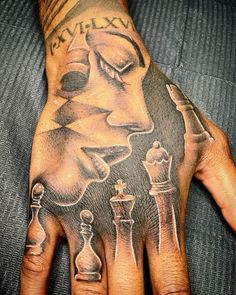 a person's hand with tattoos on it and some chess pieces in the middle