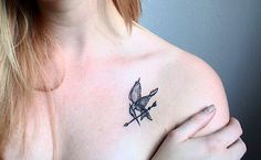 a woman with a bird tattoo on her chest and shoulder is looking at the camera