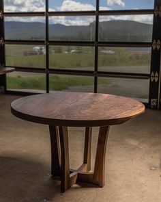 a wooden table sitting on top of a cement floor next to a large glass window