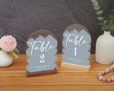 the table numbers are displayed on wooden bases with vases and flowers in front of them