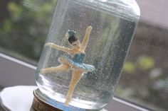 a ballerina figurine in a glass dome