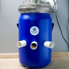 a blue water cooler with a ventilator attached to it's side on a table