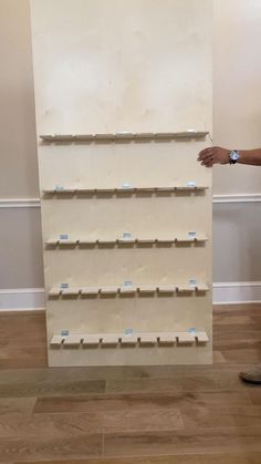 a man standing in front of a white wall with shelves on each side and blue labels on the sides