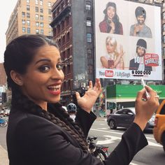 a woman holding up a sign in front of a city street with cars and buildings