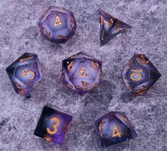 six purple and gold dices sitting on top of a gray surface with the number three