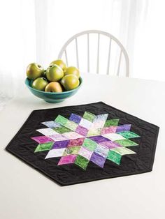 a table with a bowl of fruit on it and a quilted placemat in the shape of a star