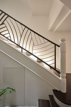 a white staircase with black handrails and a potted plant on the floor