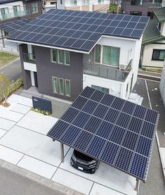 an aerial view of two houses with solar panels on the roof and one car parked in front